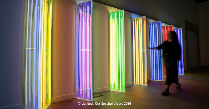 Woman walking through a colourful artwork light display named Our Spectrail Vision. 